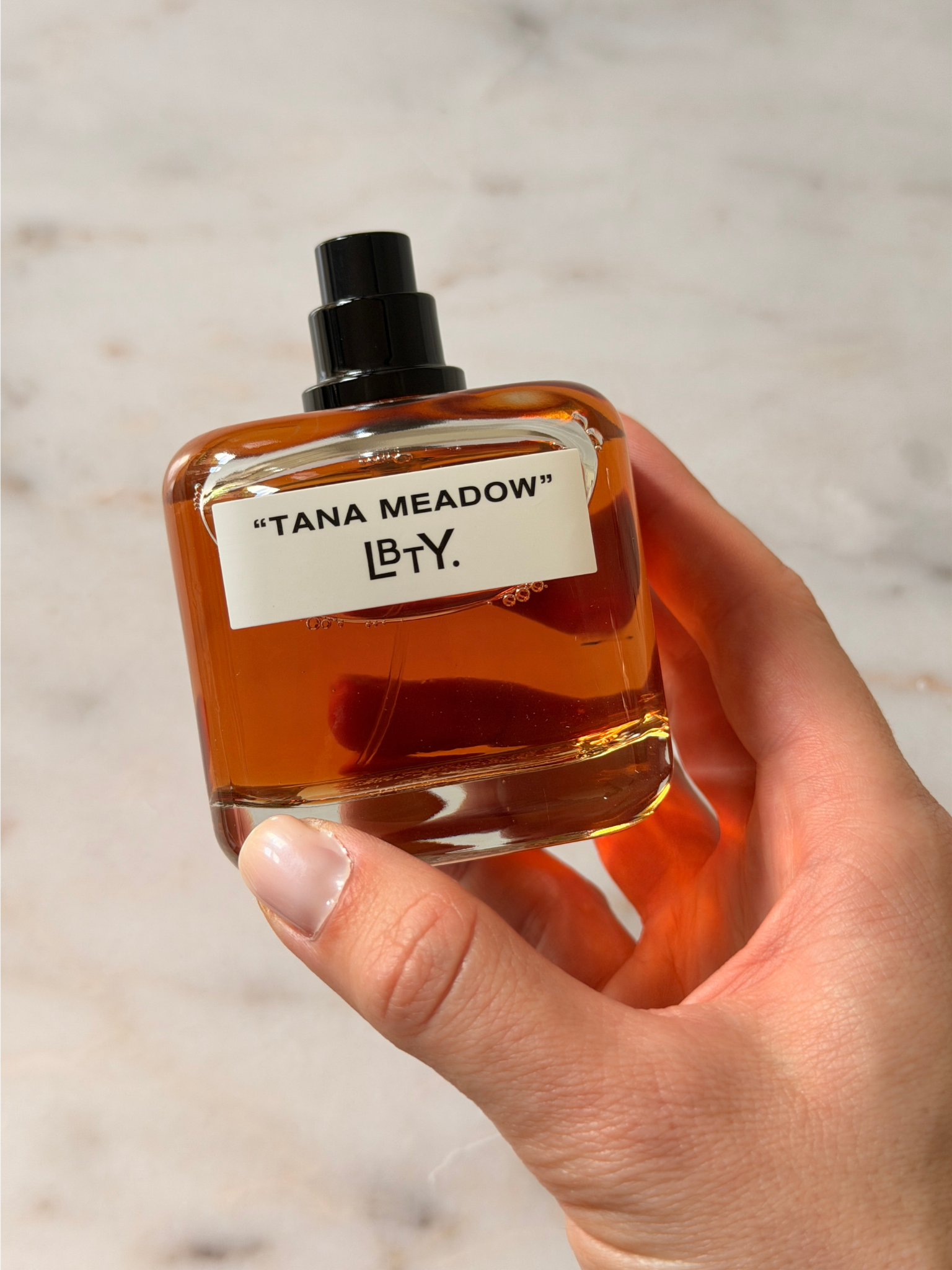 Grace holding a bottle of LBTY perfume