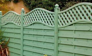 A green pressure-treated wood fence with ornate detailing
