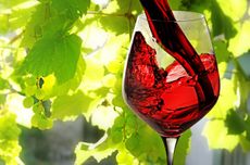 Glass of red wine on background of leaves and grapes