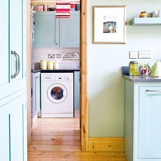 white wall with wooden flooring and washing machine with cabinet
