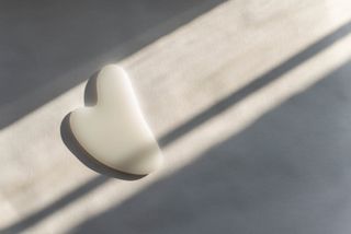 A white gua sha tool on a surface in the sunlight.