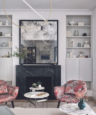 A living room with a fireplace, vintage mirror and two pink armchairs