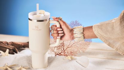 A woman with manicured nails holding a Stanley Quencher travel tumbler