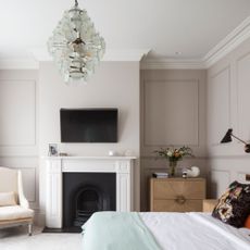 A stylish white bedroom, with a king size bed, white fireplace, and a flat screen TV