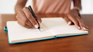 picture of woman writing a to do list in notebook