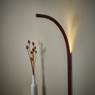 A backlit wall lamp next to a small table with flowers