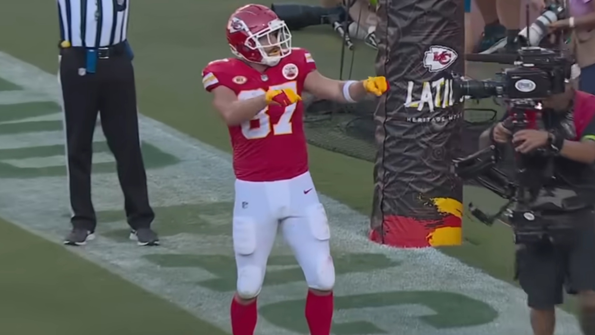 Travis Kelce is shown doing one of his signature dance moves after scoring a touchdown in a Kansas City Chiefs football game.