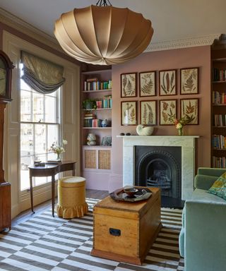 moody pink painted home office with a marble fireplace, large overheard silk light and vintage eclectic furniture