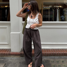 Francesca in suede flip-flops, brown trousers and a white vest
