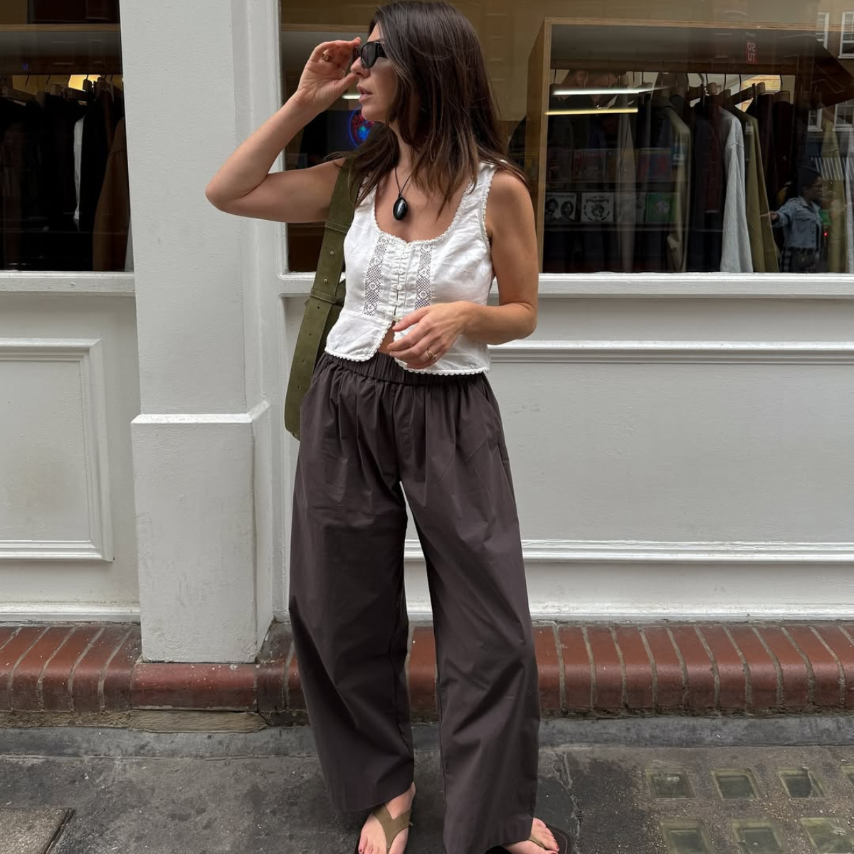 Francesca in suede flip-flops, brown trousers and a white vest