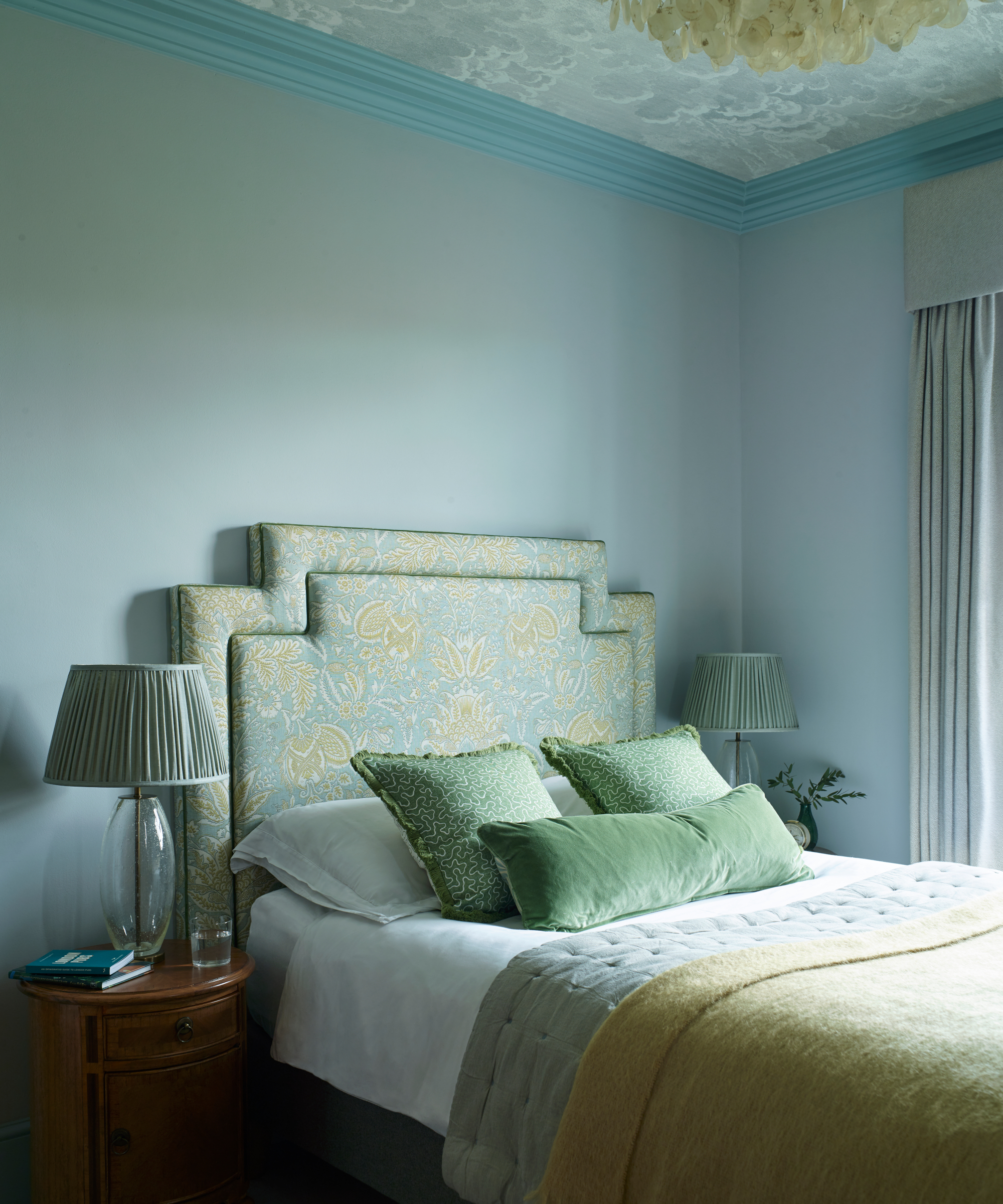 chambre bleue et verte avec papier peint nuage au plafond et tête de lit botanique en forme