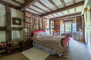 A double bed in a room with timber beams and green walls