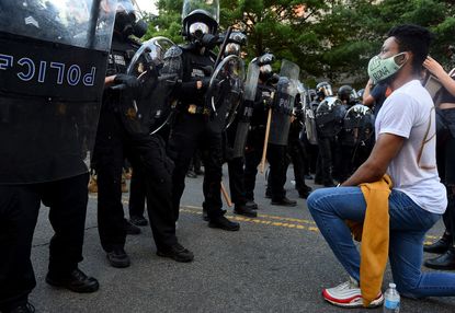 A protester kneels in front of secret service.