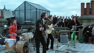 Ringo Starr, Paul McCartney, John Lennon and George Harrison perform on a roof in The Beatles: Get Back. 