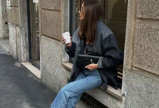 Woman wearing a gray coat with light-wash jeans.