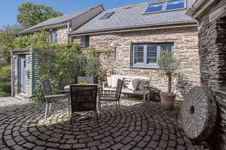 grey stone cobbles on circular patio with garden table and chairs