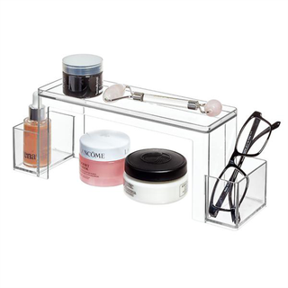 A two-tier clear acrylic storage shelf for makeup and glasses