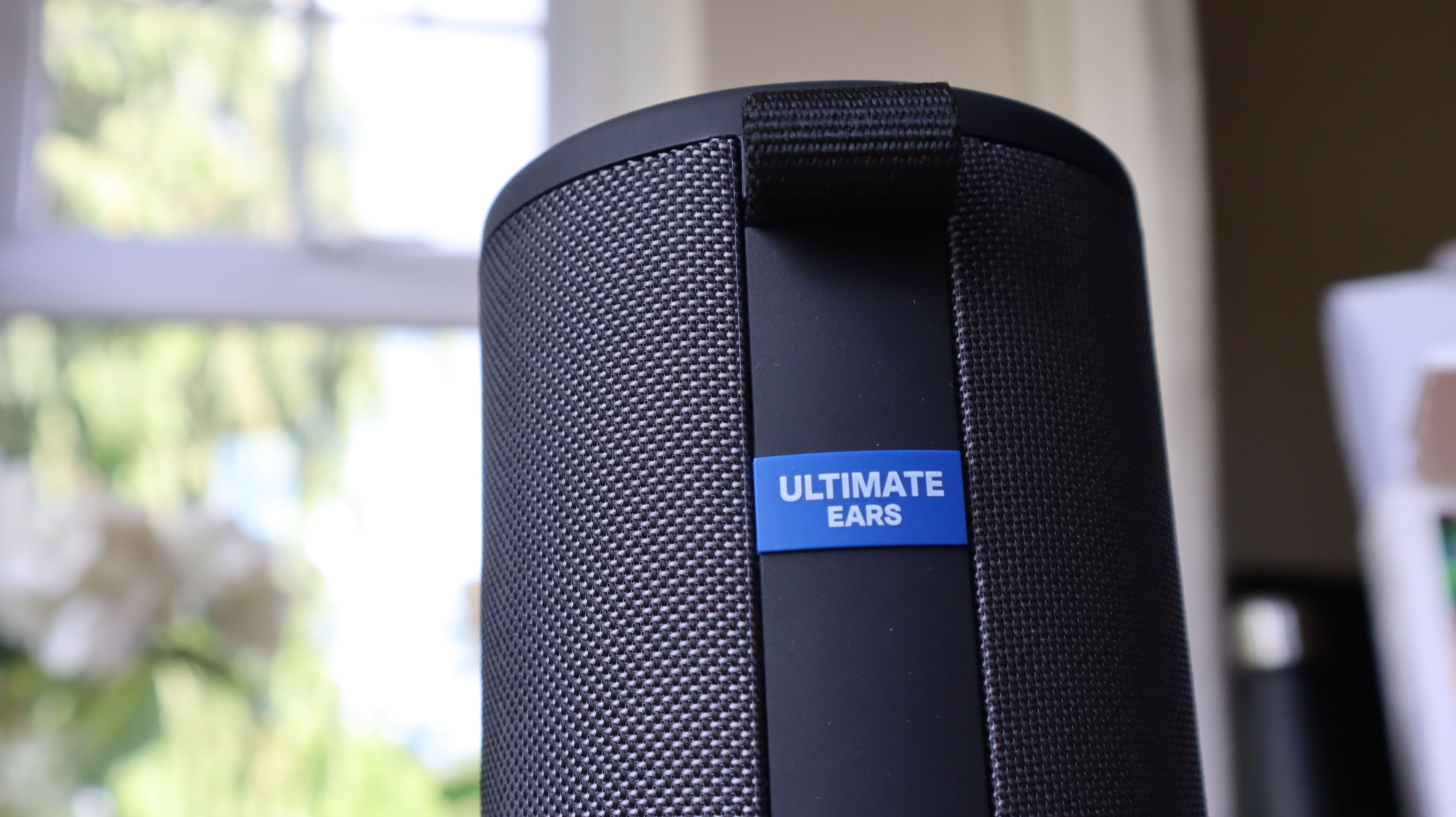 Ultimate Ears Megaboom 4 in black, in a house with white window frames in the background