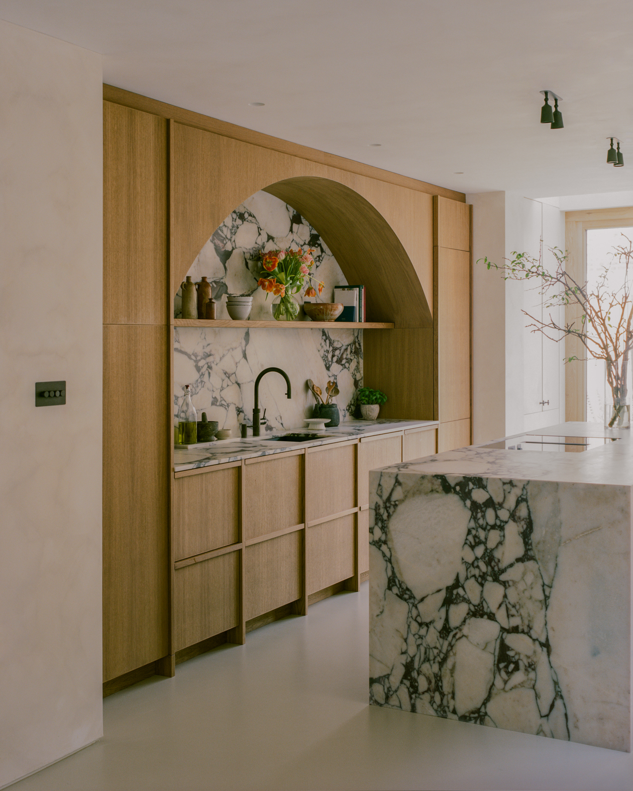 Beautiful modern kitchen with marble island and backsplash and arched wooden cabinetry