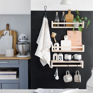 Shelving on black accent wall in kitchen storing cooking accessories