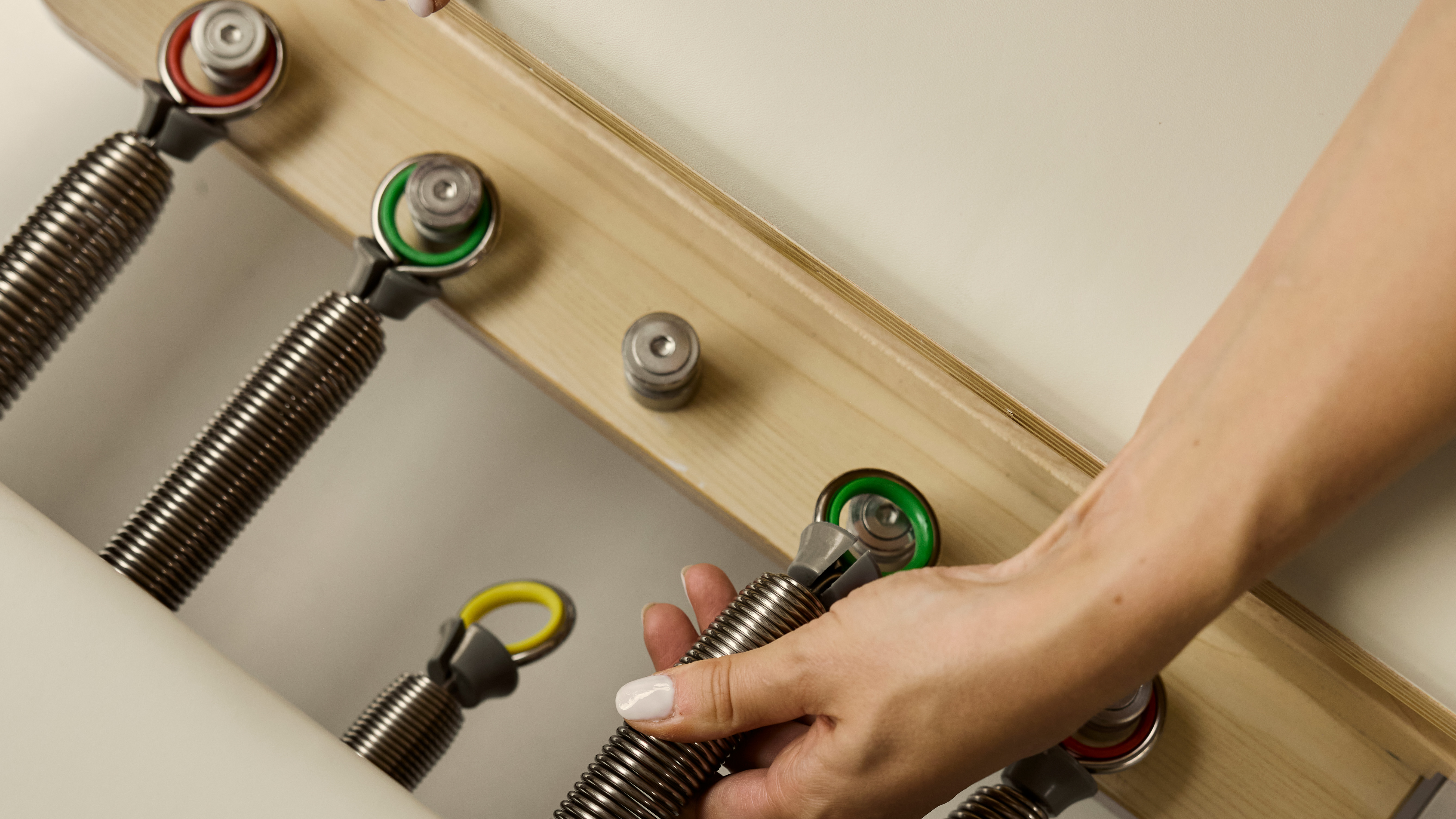 Reformer bed springs up close with woman adjusting one spring
