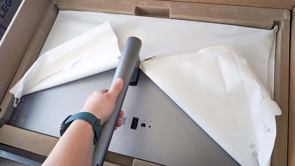Image showing Rebecca's arm pressing the stand into the back of the HP OmniStudio X AIO.