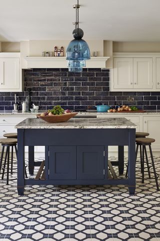 A blue and white kitchen with geometric floor tiles and a square kitchen island design and breakfast bar.