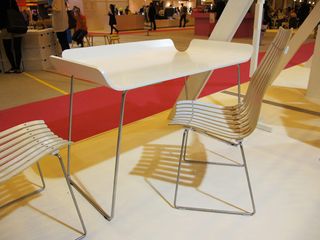 Wooden chair with metal base and matching table on display at a design event