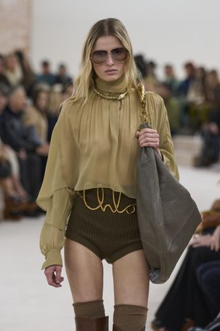 Chloé model wearing ruffled blouse and brown shorts