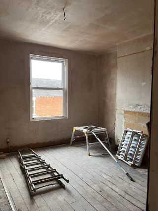 A gutted bedroom before renovation with stripped back walls and floorboards