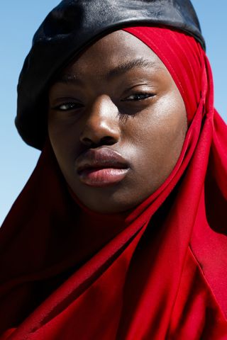 A black woman wearing a red hijab and black beret