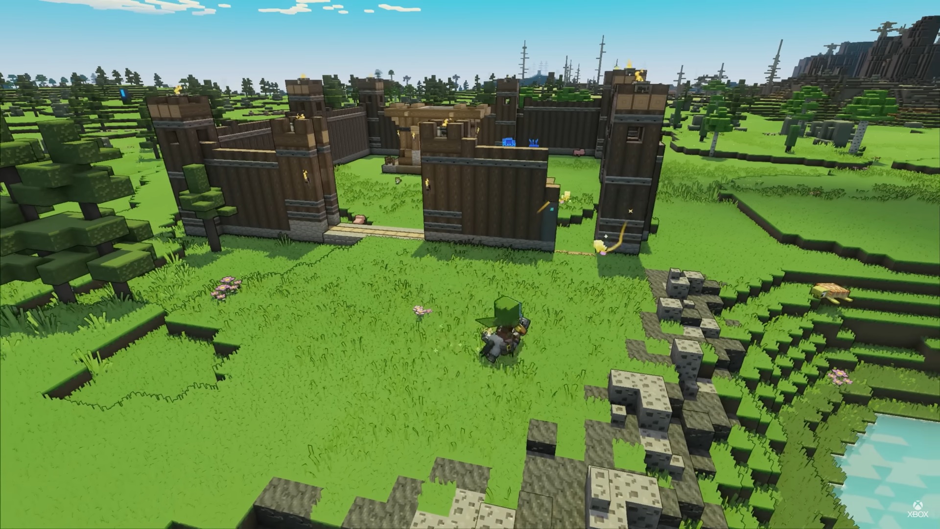 Minecraft Legends - A player on horseback in a grassy plain watches an oak log fort being built.