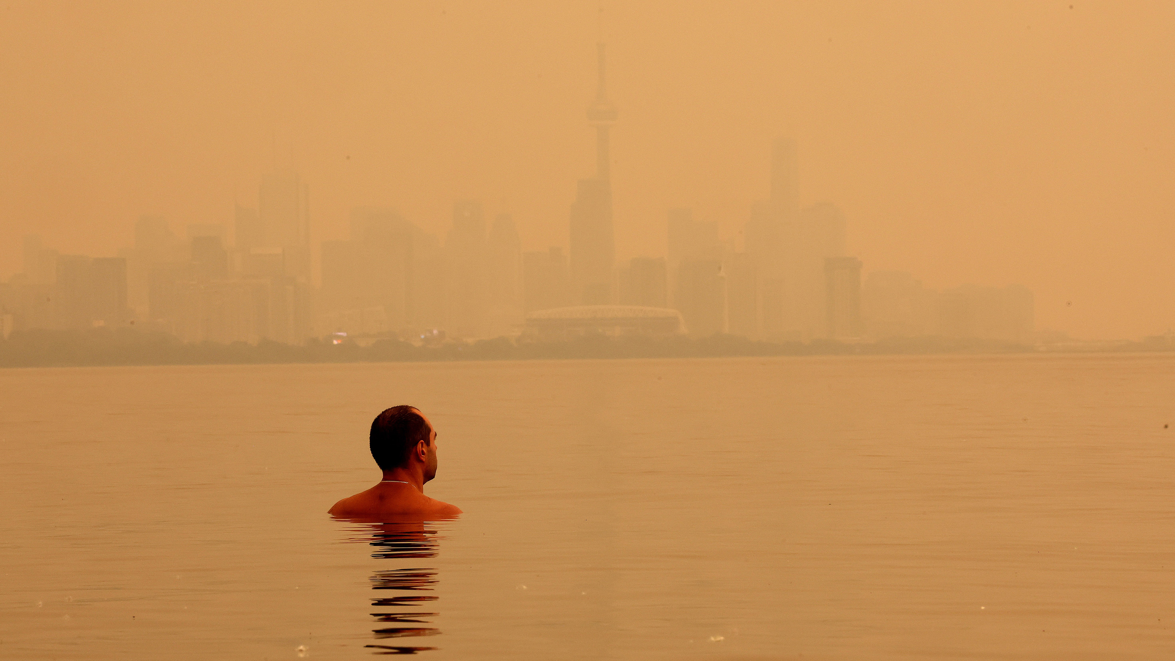 TORONTO, ON- JULY 15 - A swimmer checks out the view of the smoke from Northern Ontario forest fires that has the City of Toronto skyline shrouded in haze as viewed from Humber Park West in Toronto. July 15, 2026. Steve Russell/Toronto Star (Steve Russell/Toronto Star via Getty Images)