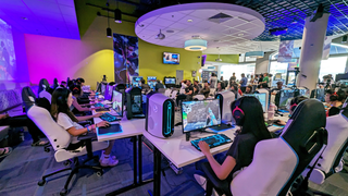 The Hawaii Pacific esports center, lit in a purple hue with college students engaged. 