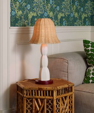 Rattan table light by David Netto with white and red base on a bamboo side table and green wallpaper