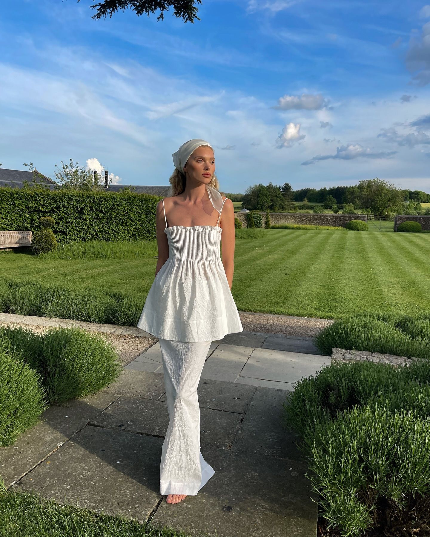 Elsa Hosk wearing a white waistcoat and skirt with a headscarf