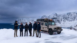 A group of men stood next to a truck in the arctic.