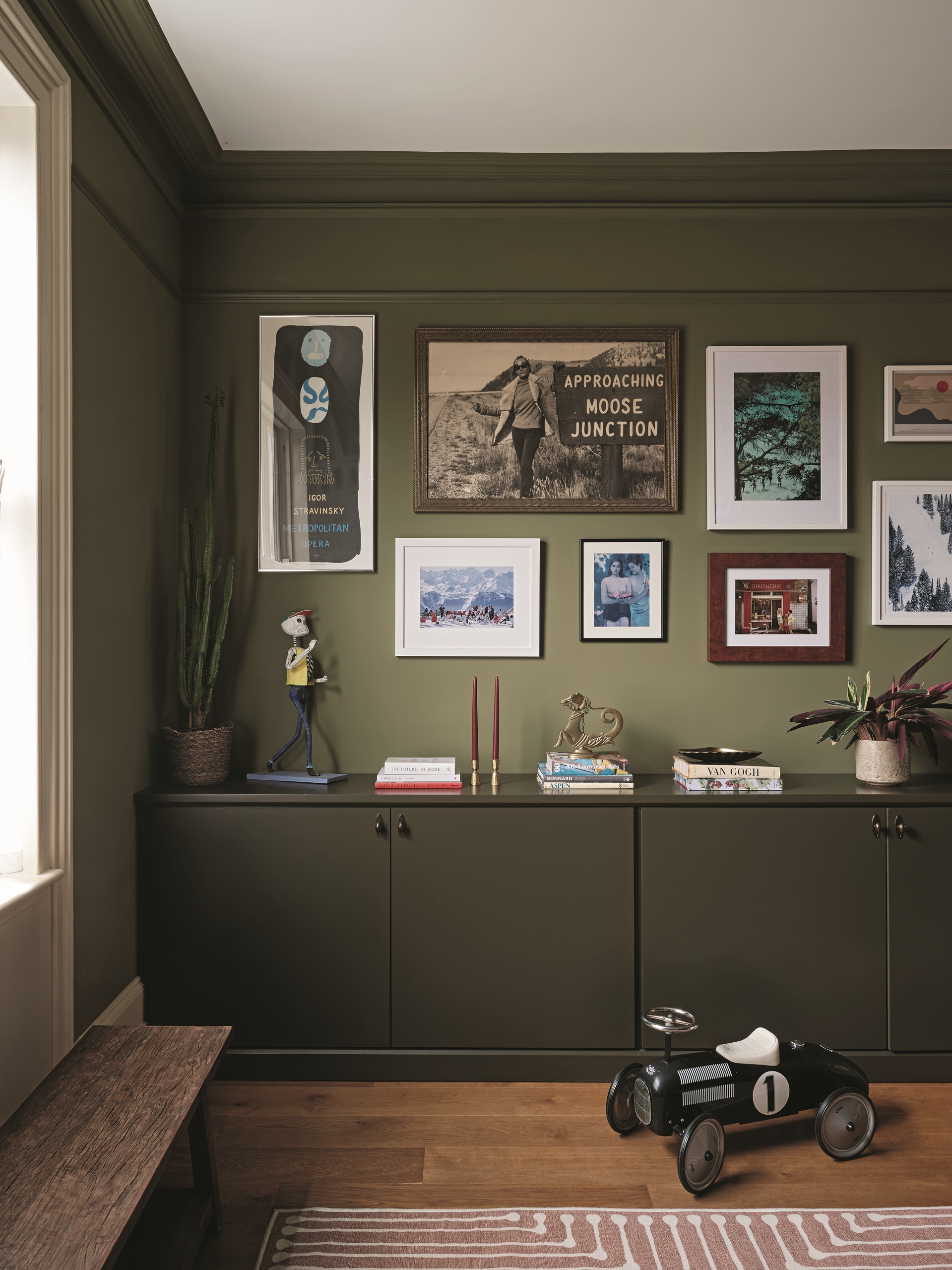a green gallery wall with cabinets in front