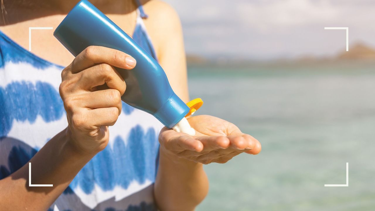 woman applying sunscreen while wearing a blue summer dress, needing to know how to get sunscreen out of clothes