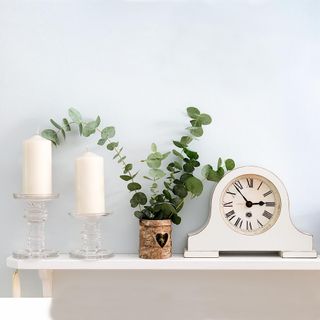 light blue wall shelf on wall with candles plant and clock