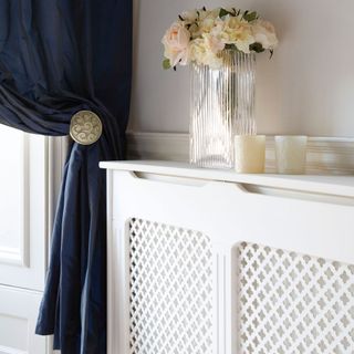 blue curtains with white cabinet flower in vase and white walls