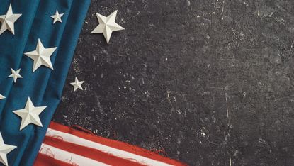 partial view of american flag with white stars on top and black background