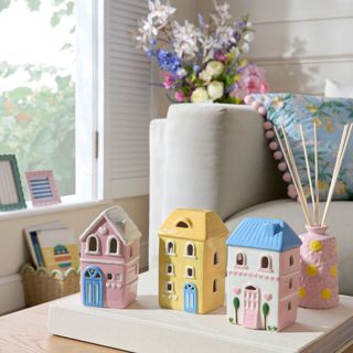 A living room with the coffee table decorated with pink flower-design reed diffuser and pastel light-up houses