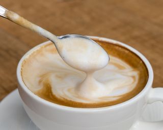 A coffee with froth on a teaspoon