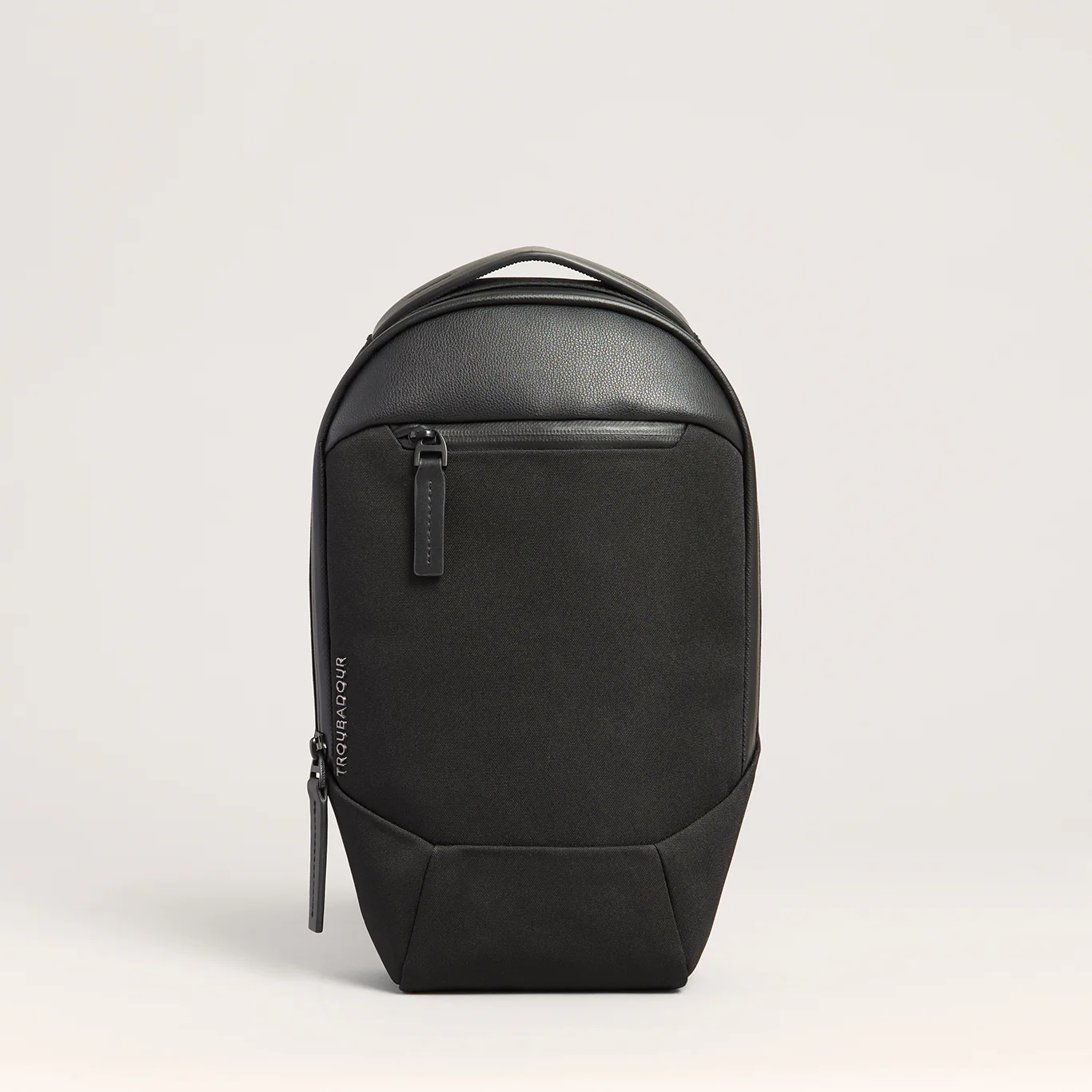 The Troubadour Apex Sling backpack on a grey background.