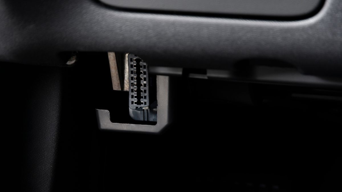A car's OBD2 port under a dashboard
