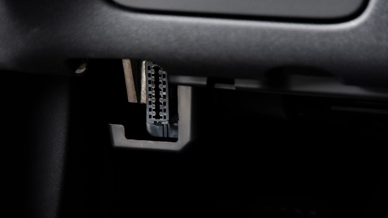A car's OBD2 port under a dashboard