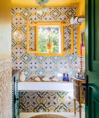 A colorful bathroom with patterned tile, yellow walls and ceiling, and a green door