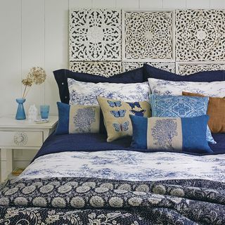 bedroom with plush velvet bed headboard and printed cushion