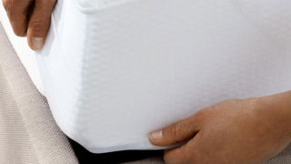 How to clean a memory foam mattress: person fitting a mattress protector